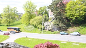 A road with a bus and cars, surrounded by greenery and a rock formation. - Russell Hotel (Royal Tunbridge Wells)