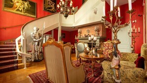 Une vaste pièce dotée d’un escalier, d’un lustre et d’une cheminée.