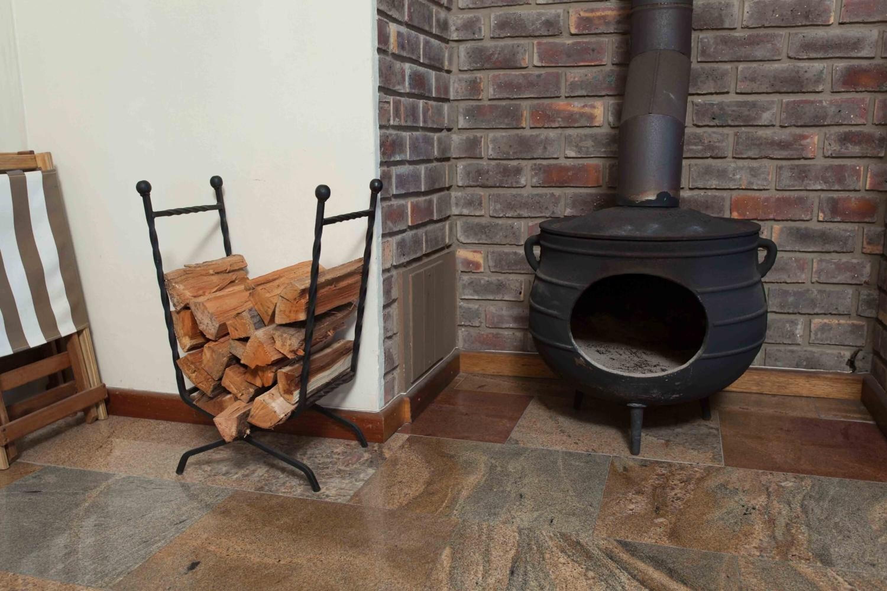 Una habitación con pared de ladrillo, un estufa de leña y una pila de leña.