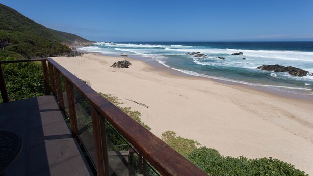 A beach with a wooden deck and railing, overlooking the ocean and a hillside. - ArchRock Resort (Keurboomstrand)
