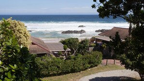 A coastal property with a view of the ocean, a gravel driveway, and a fenced yard. - ArchRock Resort (Keurboomstrand)
