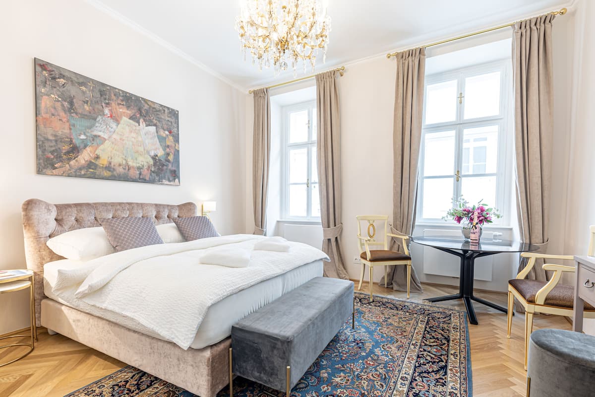 A spacious bedroom with a large bed, a bench, a desk, and a chair.