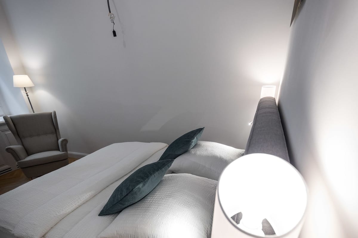 A modern bedroom with a bed, bedside lamp, and a chair.