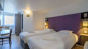 A hotel room with two beds, a desk, and a chair.