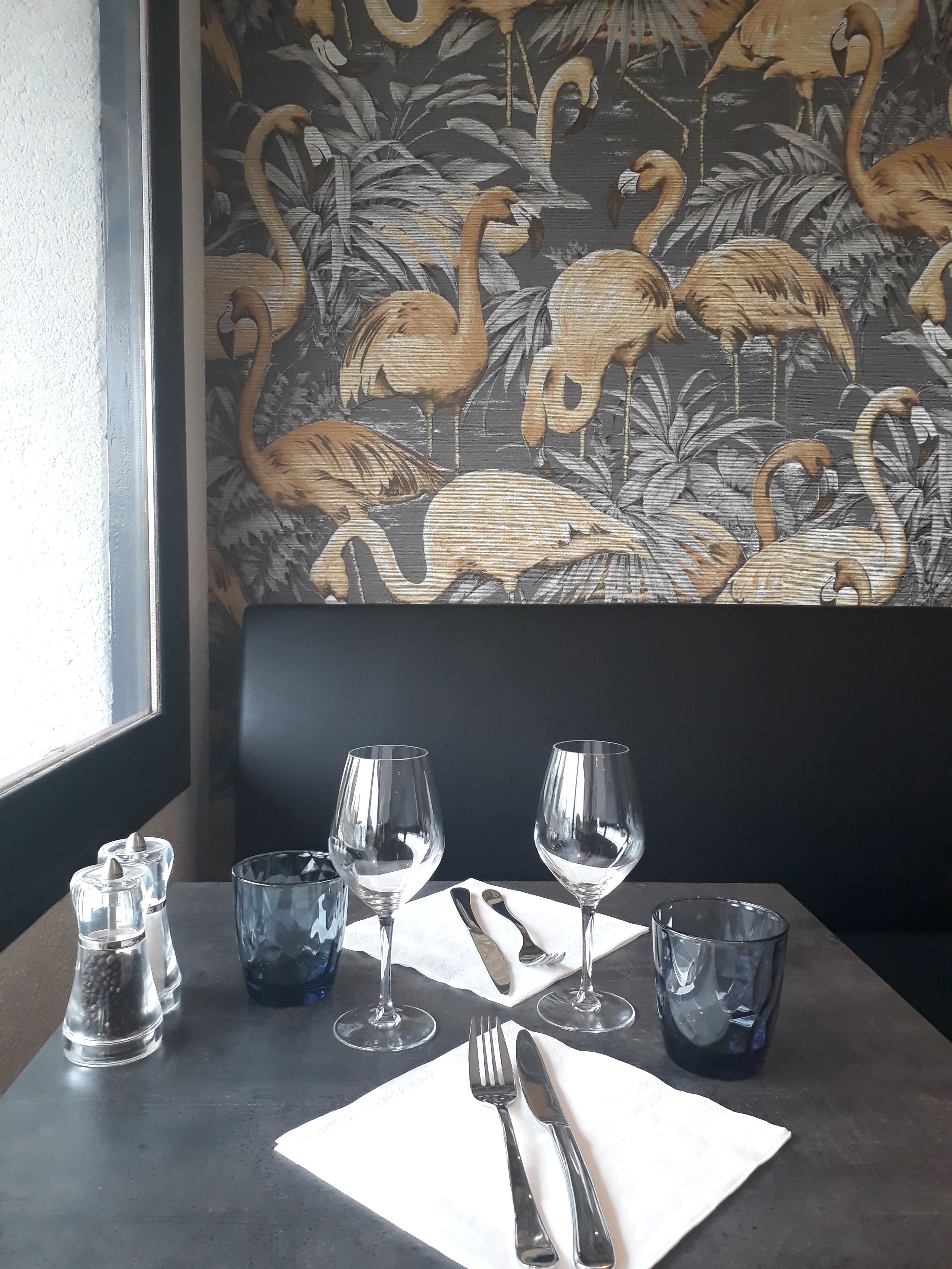 Une table à manger dressée avec des verres à vin, des couverts et des salières et poivrières.