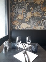 Una mesa de comedor dispuesta con copas de vino, cubiertos y saleros y pimenteros.