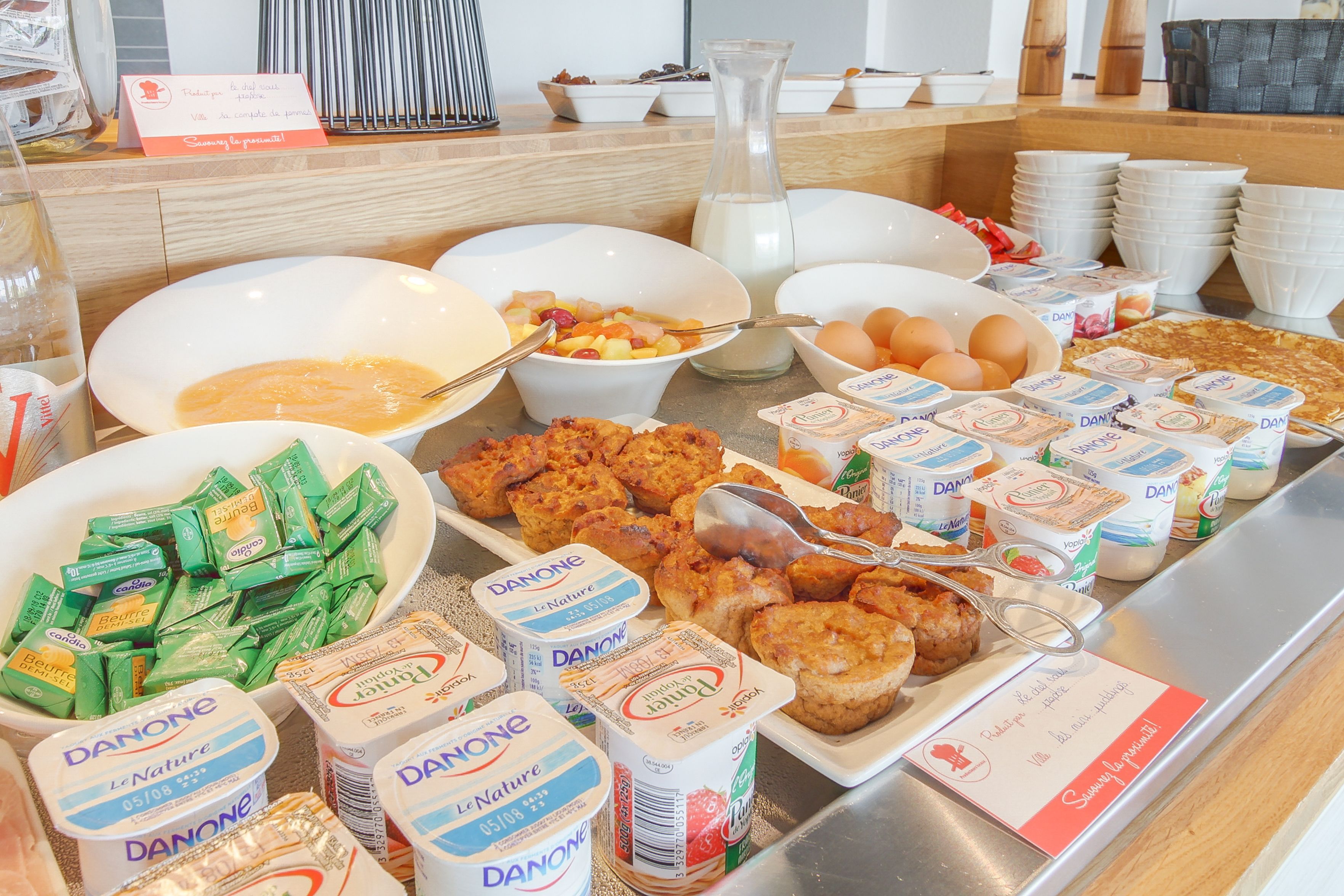 A buffet with various food items including Danone yogurt, eggs, and pastries.