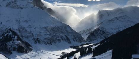 A snow-covered mountain landscape with a valley and a few buildings.