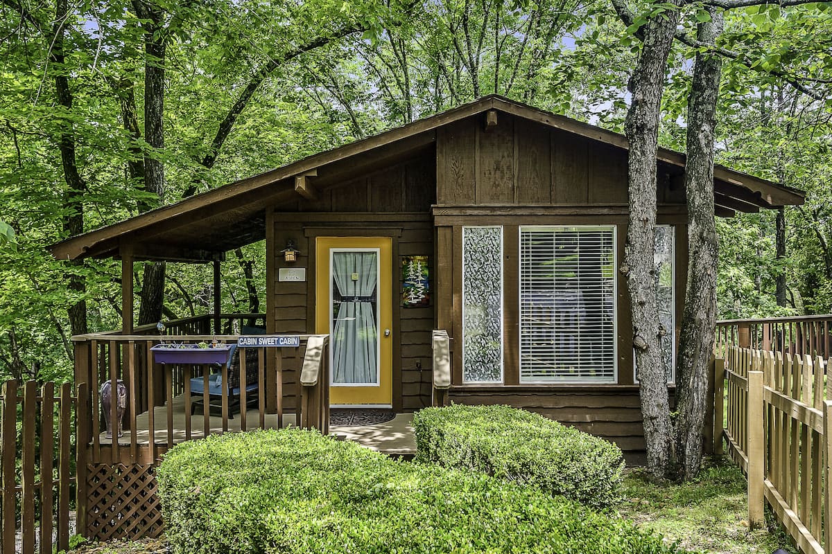 A cabin with a wooden exterior, a porch, and a small deck.