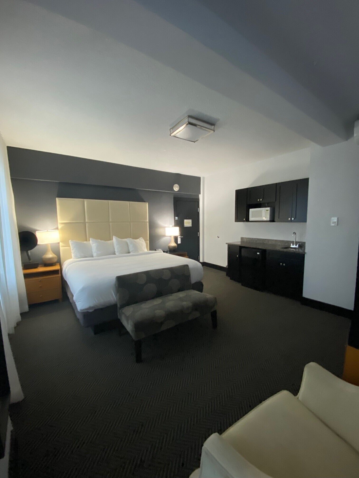 A hotel room with a large bed, a desk, a microwave, and a small kitchenette.