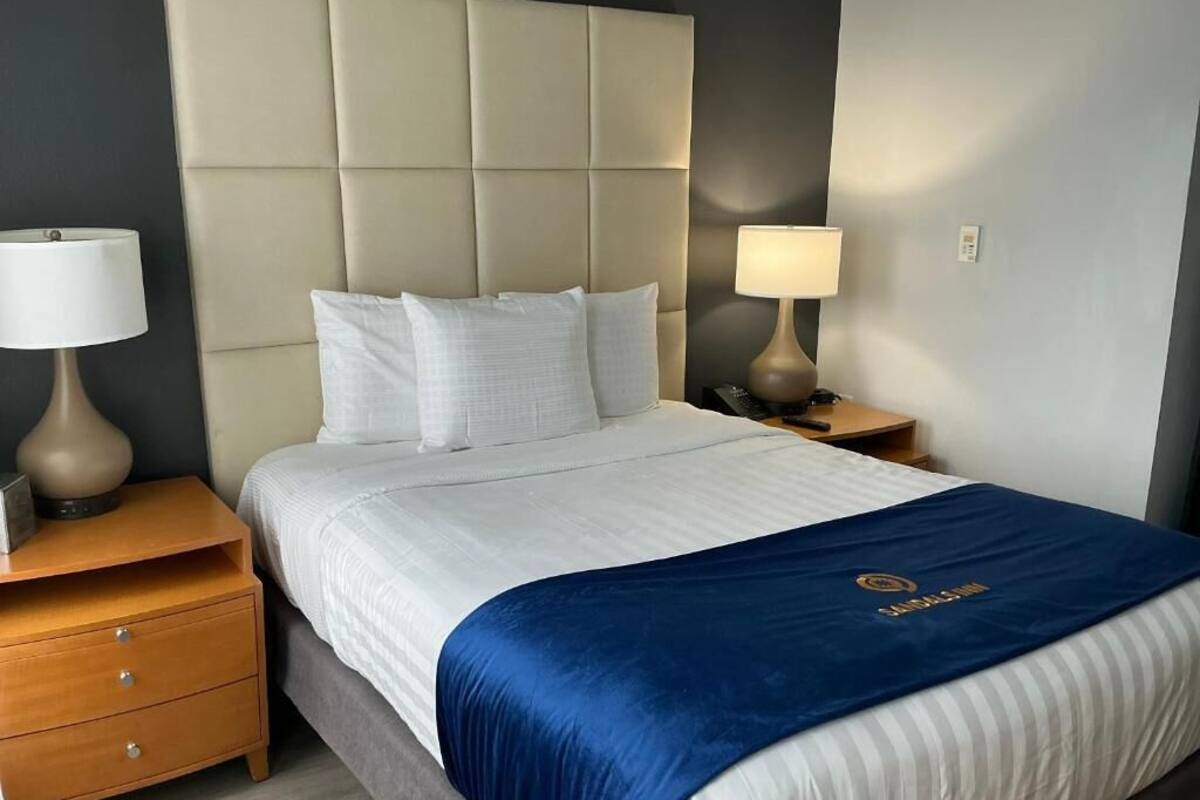 A hotel room with a large bed, two bedside tables, and a headboard.