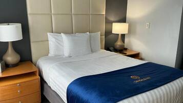 Quarto de hotel com uma cama grande, duas mesinhas de cabeceira e cabeceira.