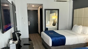 Une chambre d’hôtel avec un lit, une table de chevet et un miroir.
