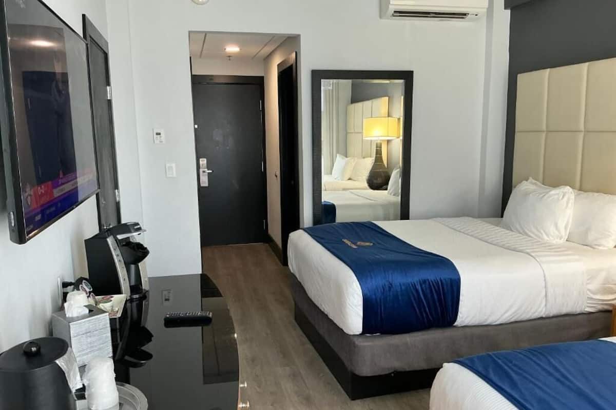 A hotel room with a bed, bedside table, and a mirror.