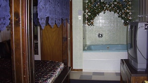 A small, compact room with a single bed, a bathtub, and a television. - Cedar Grove Motel (Altoona)