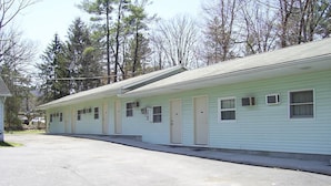 A row of motel rooms with individual doors and windows, a parking lot, and a forested background. - Cedar Grove Motel (Altoona)
