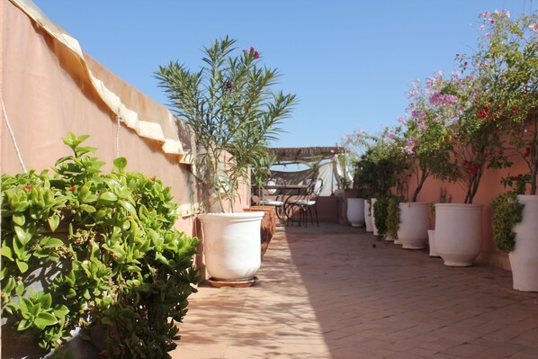 An outdoor patio area with potted plants, a pergola, and a tiled floor. - Riad du Ciel Marrakech (Marrakech)