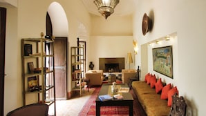Una sala de estar con un sofá, sillones, una mesa de centro, chimenea y estantería.