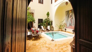 Un patio interior con piscina, zona de estar y un cuadro grande en la pared.