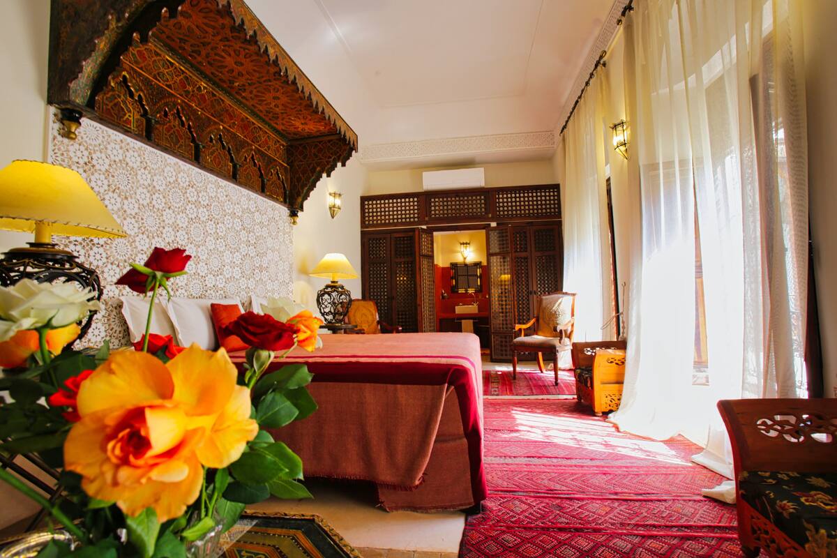 A traditional room with a bed, a chair, a table, and a decorative wall.