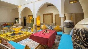 A traditional Moroccan interior with a fountain, a dining area, and a large decorative vase. - Riad Hotel El Kennaria (Marrakech)