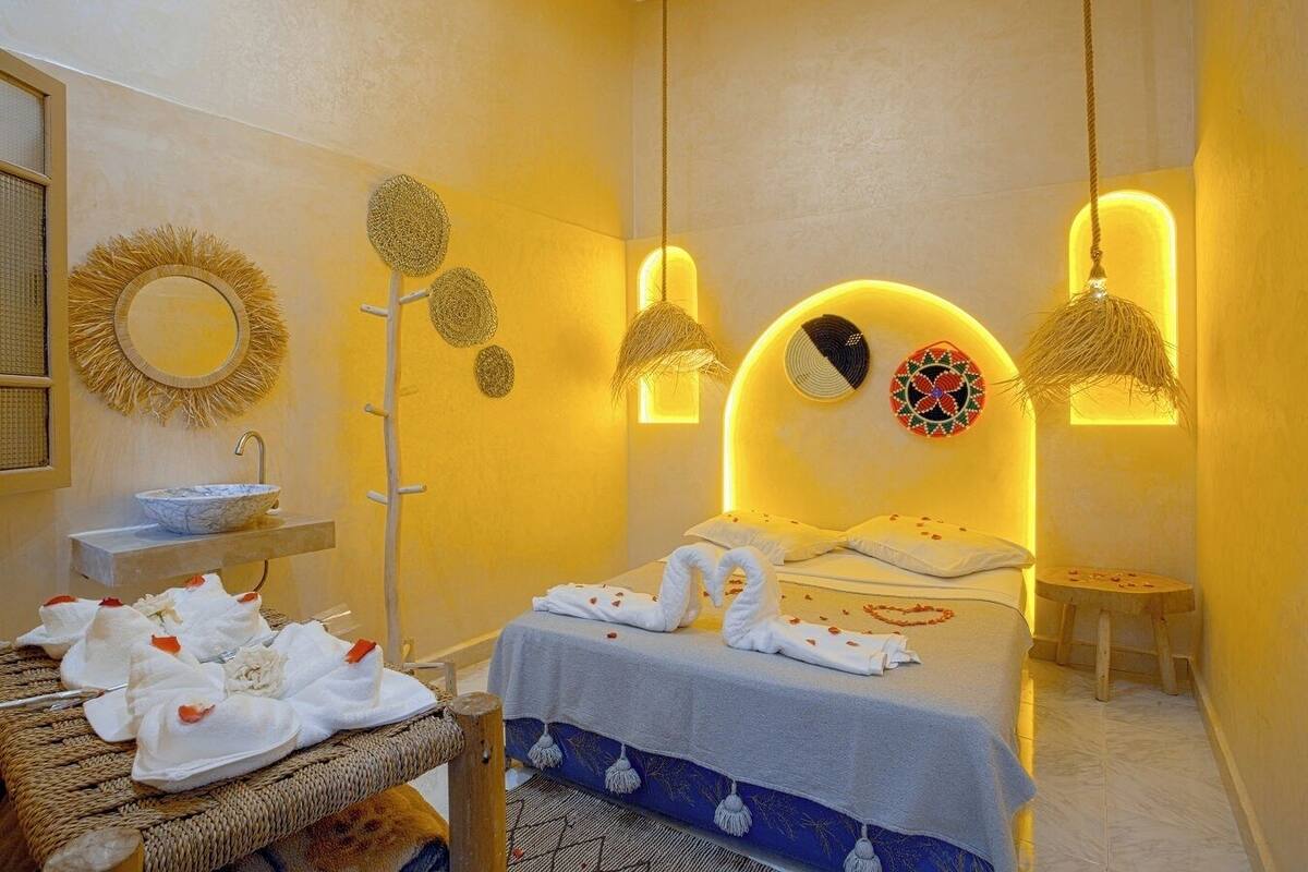 Habitación de hotel con una cama, una mesita de noche con toallas, un espejo montado en la pared y decoración en la pared.