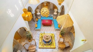 A high-ceilinged lounge area with a central seating arrangement, patterned floor tiles, and hanging lamps. - Riad Hotel El Kennaria (Marrakech)