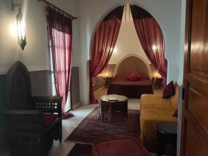 A room with a bed, a sofa, a small table, and a chair.