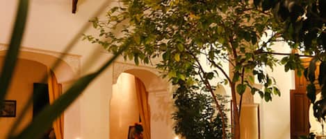 Un comedor interior con mesas y sillas, una fuente y un ambiente con velas.