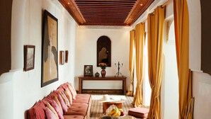 A hallway with a sofa, a table with fruit, and a mirror. - Riad Marelia (Marrakech)
