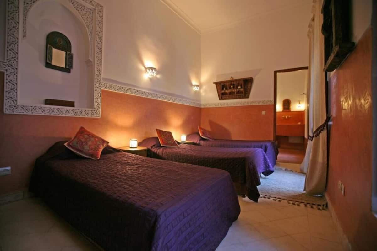 Hotellihuone, jossa on kaksi sänkyä, peili ja seinävalaisimet.