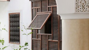 A traditional building with a wooden balcony and lattice window. - Riad Marelia (Marrakech)