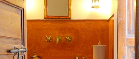A bathroom with a wooden vanity, a mirror, a towel, and a wall-mounted light fixture.