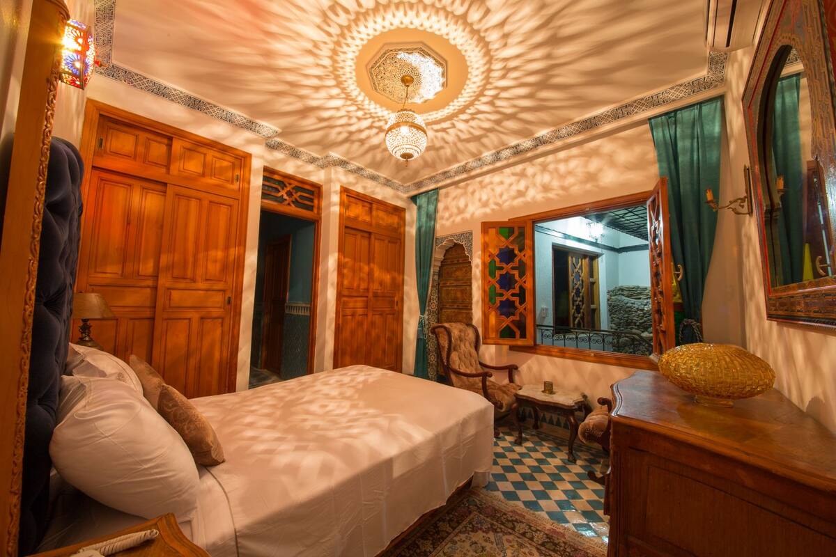 Una habitación con cama, una silla, una mesa y un espejo.