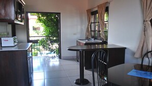 A compact kitchen with a dining area, a window with curtains, and a view of greenery outside. - Hotel Real Granada (Granada)