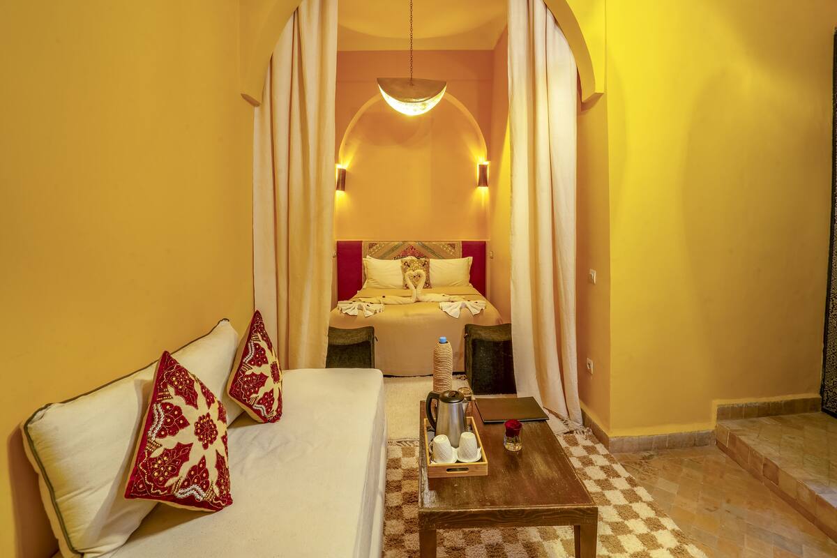 Una habitación de hotel con sofá, mesa de centro, cama y candelabro.