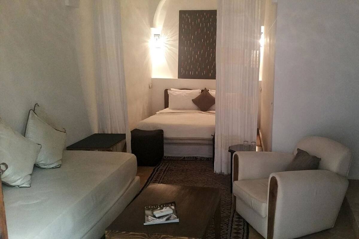 Habitación de hotel con cama, sofá, silla, una mesita y una revista en el suelo.