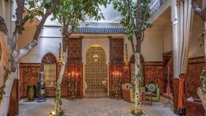 Une cour traditionnelle agrémentée de portes richement décorées, d’une fontaine centrale et d’espaces aménagés pour s’asseoir.