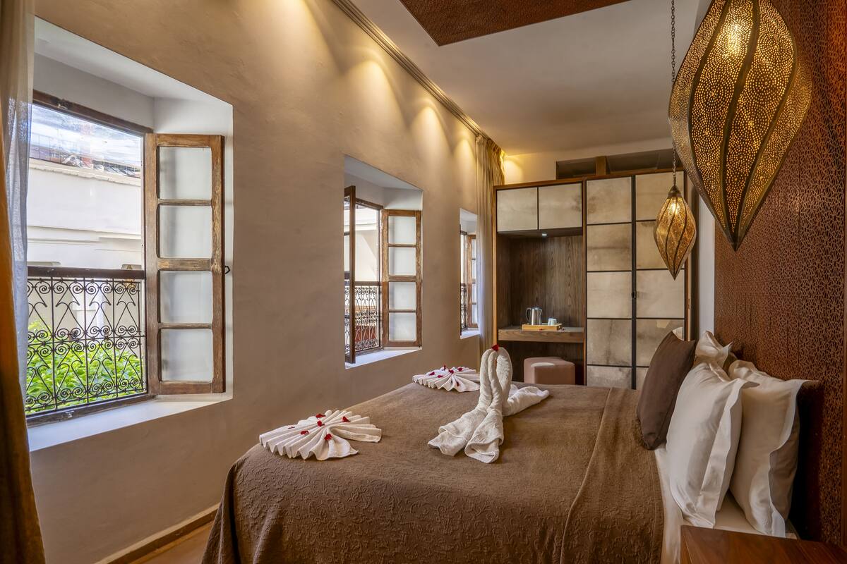 Una habitación de hotel con una cama grande, dos ventanas, un escritorio y un adorno en la pared.