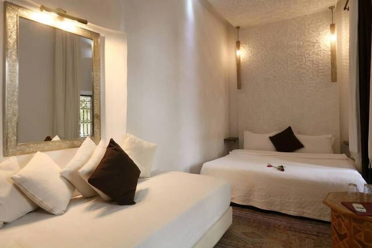 Habitación de hotel con dos camas, un espejo grande y una mesita pequeña.