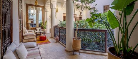 A traditional courtyard with a sofa, potted plants, and hanging lamps.