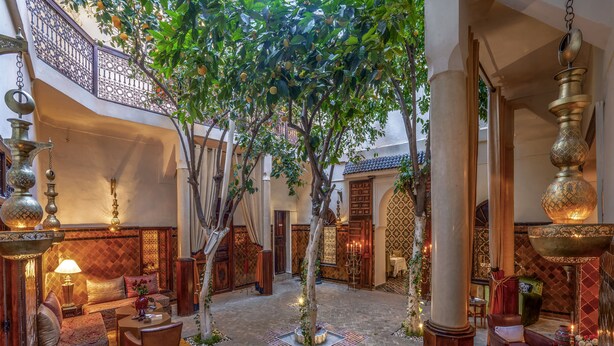 Un intérieur traditionnel avec une cour intérieure, des portes richement décorées et une lampe suspendue.