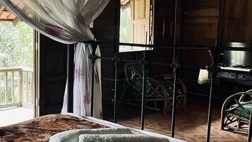Una habitación con cama, una silla, un escritorio y una ventana con cortinas.