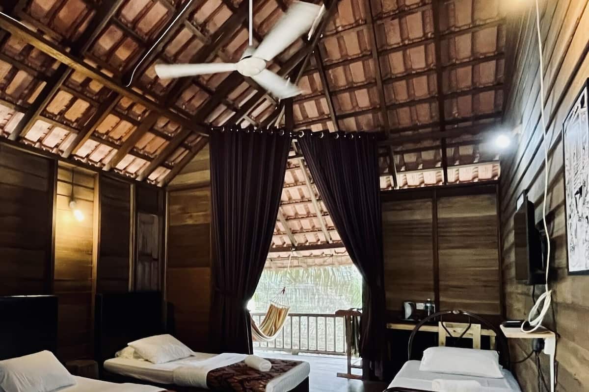 A room with two beds, a desk, a chair, and a ceiling fan.