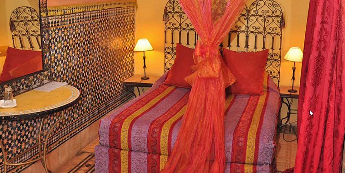 A room with a bed, a round table, and a patterned wall.