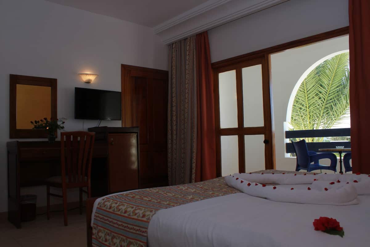 Une chambre d’hôtel équipée d’un lit, d’un bureau, d’une chaise, d’une télévision et offrant une vue sur l’extérieur.