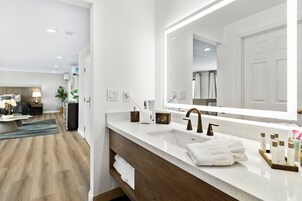 Un baño moderno con un espejo grande, un lavamanos y un mueble de tocador de madera.