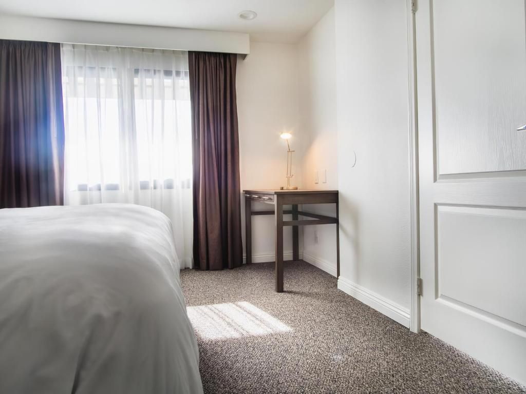 Une chambre d’hôtel avec un lit, un bureau et une porte.