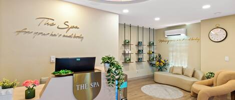 Ein Spa-Empfangsbereich mit modernem Design, darunter eine Rezeption, eine Sitzecke und ein Wandregal mit Spa-Produkten.
