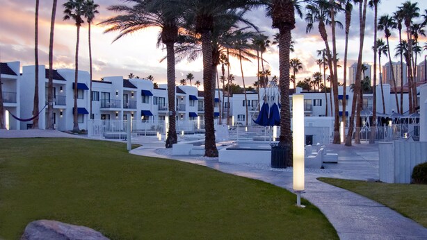 Un resort con varias edificaciones blancas, palmeras y un césped cuidado.
